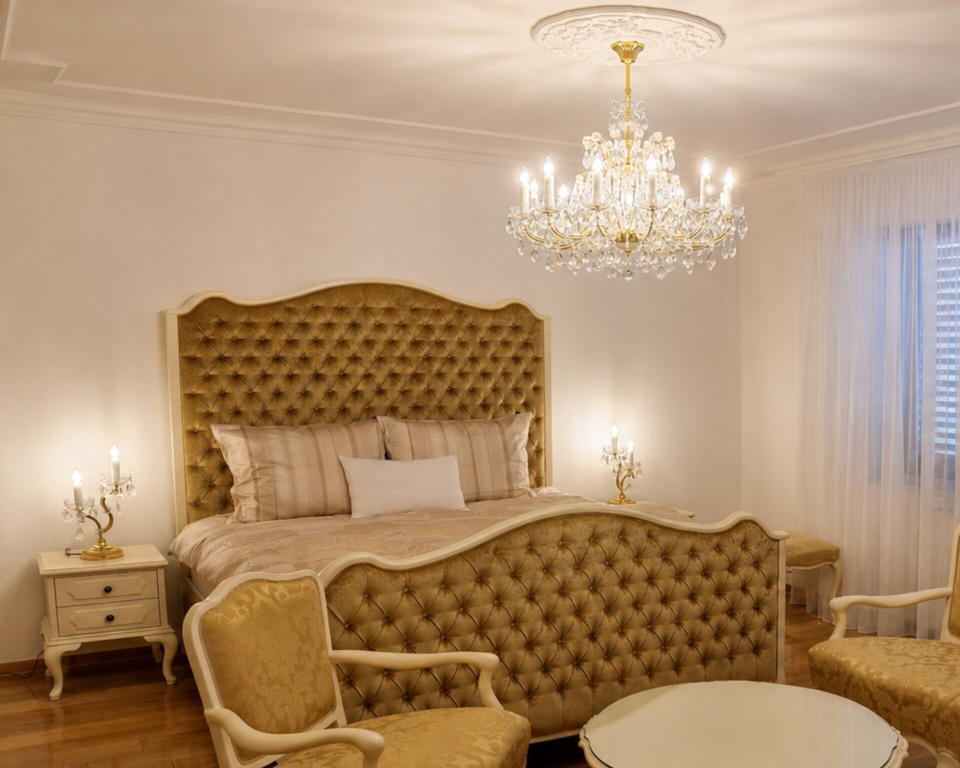 Dormitorio principal de estilo neobarroco con una gran lámpara de araña de cristal de estilo María Teresa sobre la cama