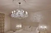 Lámpara de cristal María Teresa en acabado plateado sobre la cama en un dormitorio de lujo con apliques de pared