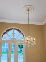 Lámpara de cristal con bombillas de vela colgada en un rincón con ventana arqueada